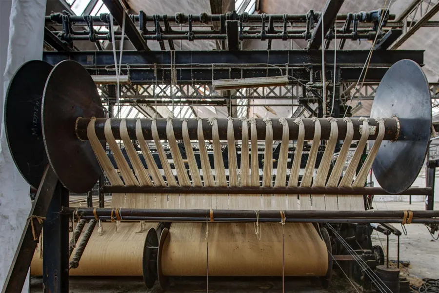Rodillo textil ancho con hilos paralelos junto a guías metálicas.