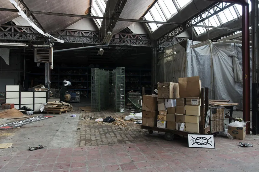 Carro con cajas de cartón entre materiales sueltos en la nave.