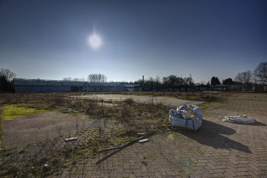 Verlaten bestraat buitenterrein met een grote witte afvalzak.