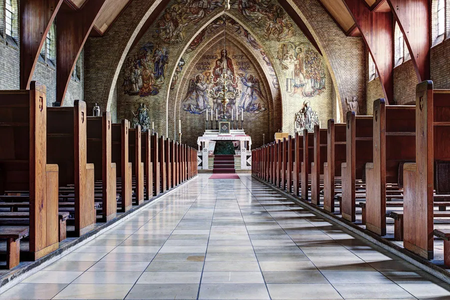 Low viewpoint along the central aisle towards the altar and a large religious mural.