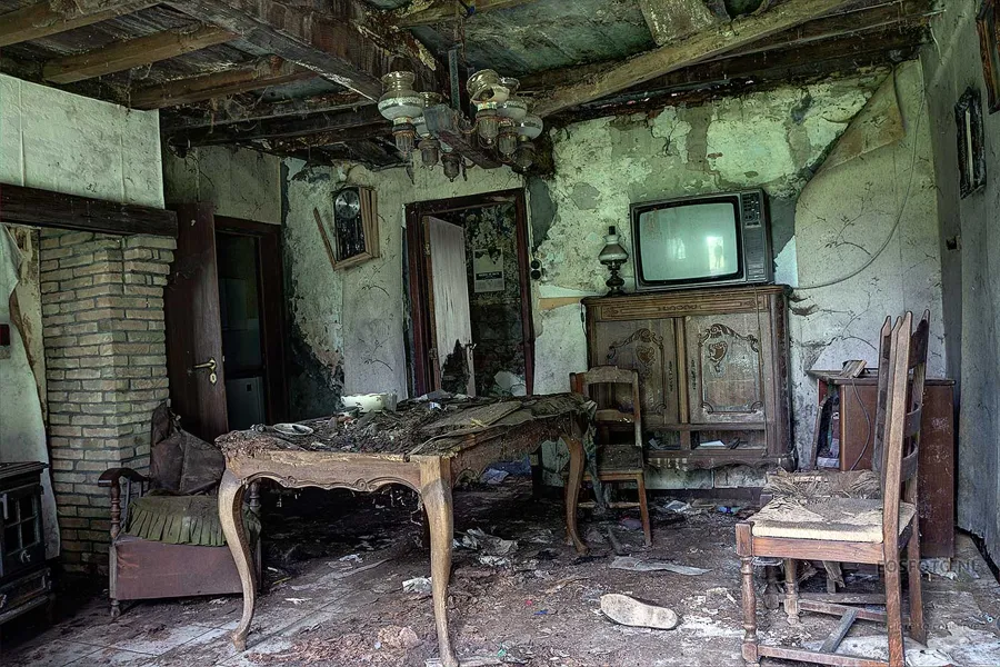 Table, chaises et téléviseur entre des murs dégradés