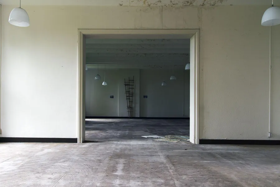 Twee lege lichte zalen verbonden door een brede open doorgang.
