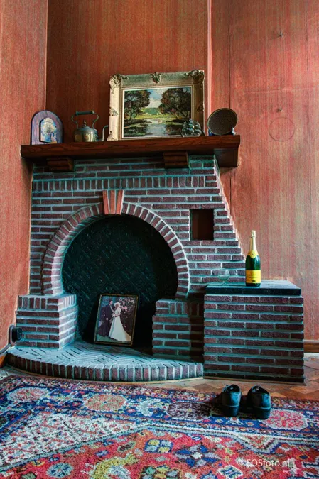 Brick fireplace with a bottle and shoes on a rug.