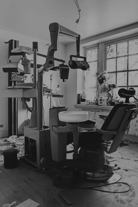 Dentist’s chair with old equipment beside the window, in black and white.