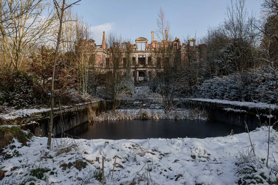 Schlossruine hinter einem Teich in einem verschneiten Garten