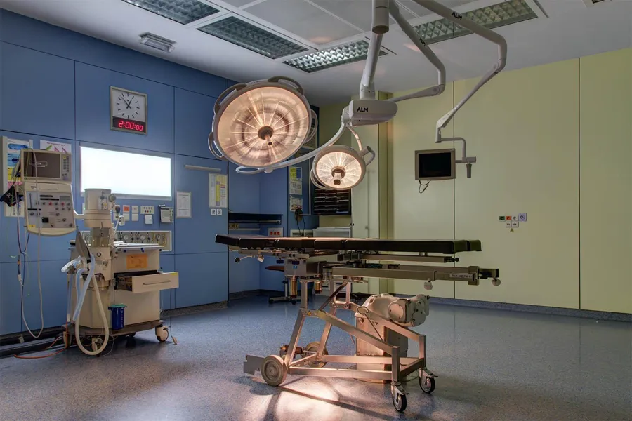 Warmly glowing surgical lights above a table in an empty operating room.