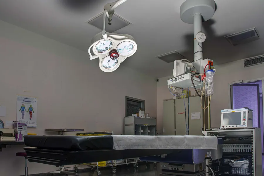 Tiefer Blick an leerem OP-Tisch entlang zu Lampen und Geräten an der Decke.