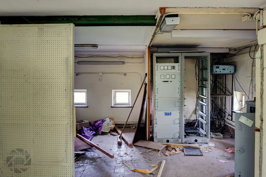 Open equipment cabinets and loose panels in a small room with debris.