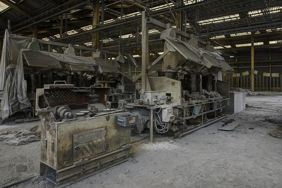 Lange stoffige productiemachine met meerdere open kappen.