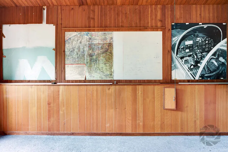 Wooden classroom wall with blackboard, map and a photograph of an aircraft cockpit.