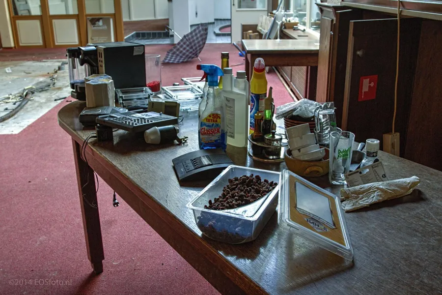 Botellas, tazas y envases abandonados sobre una mesa de madera.