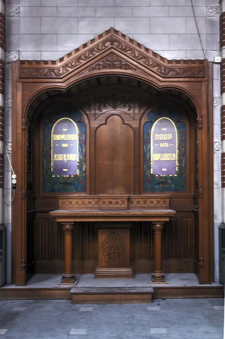 Mueble religioso mural de madera con dos paneles violetas y remate tallado.