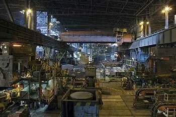 Wide view through the production hall, with machines on both sides and an overhead crane track.