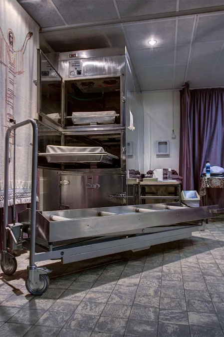 Mesa metálica con ruedas y compartimentos abiertos en la morgue.