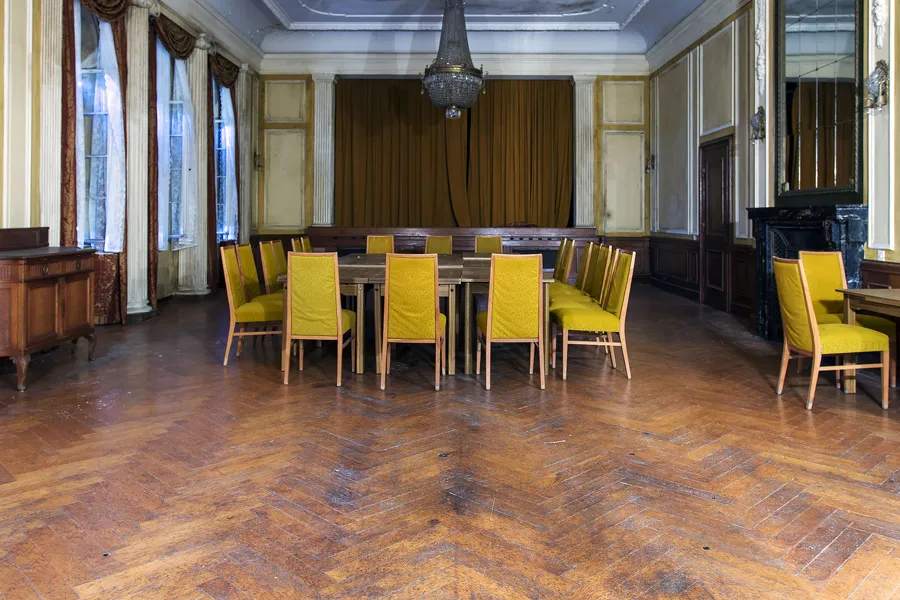 Eetzaal met lange tafel, gele stoelen en parketvloer