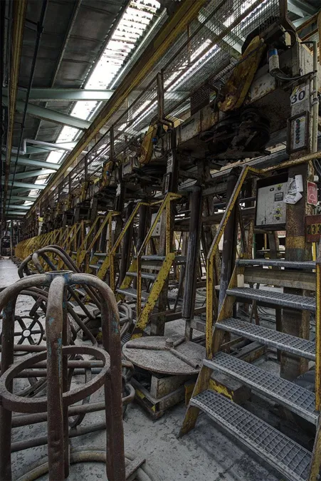 Metalen trappen en grote handwielen langs machines.