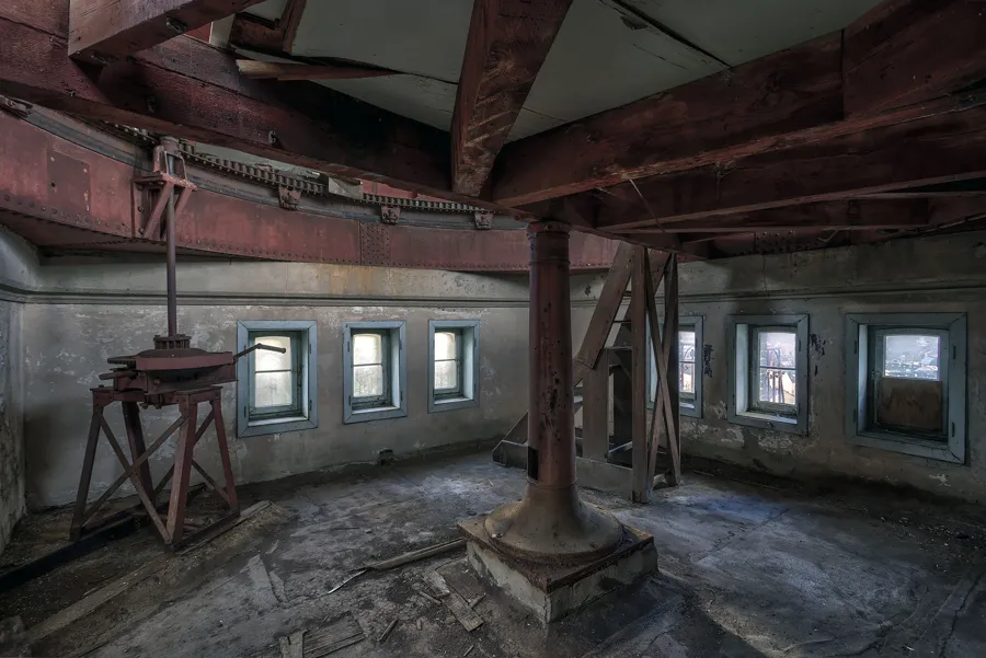 Sala circular con columna metálica central y pequeñas ventanas alrededor.