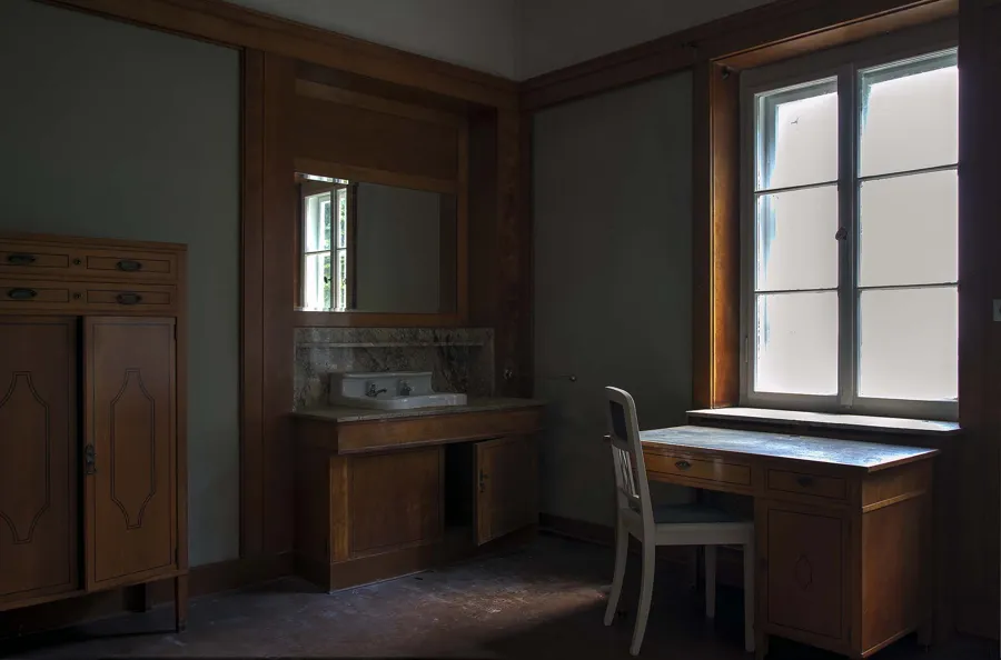 Houten bureau, stoel en kast in een sobere kamer