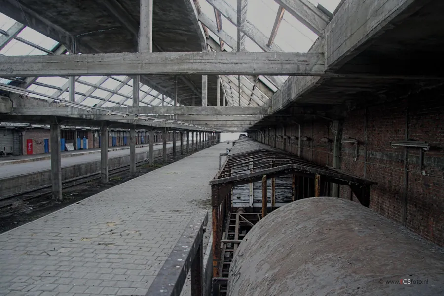 Blick an einem Wagen entlang zum langen Bahnsteig unter Betonbalken.