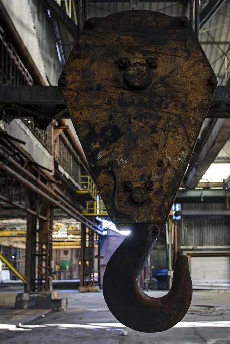 Grand crochet de grue rouillé vu de près dans une haute halle.