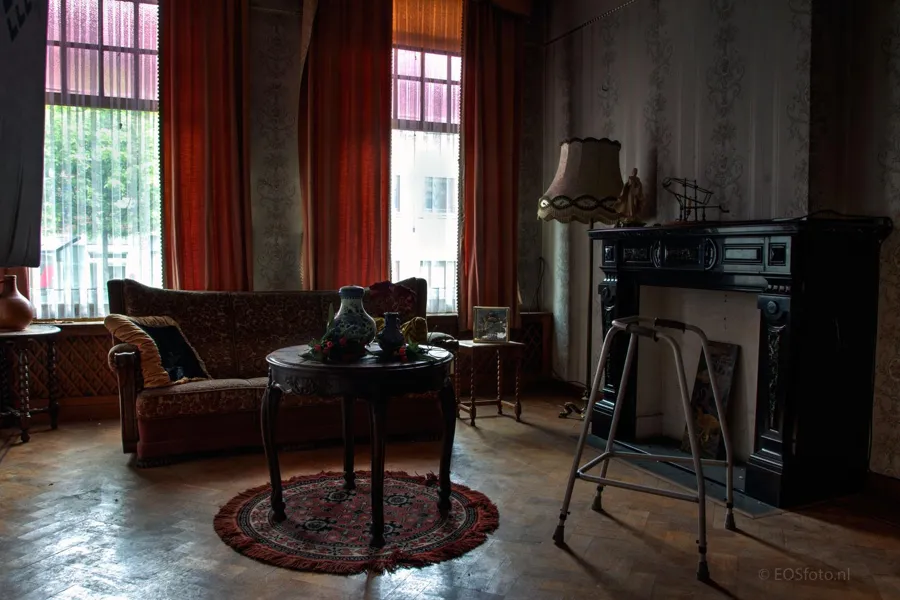 Seating area with a low round table and tall red-curtained windows.