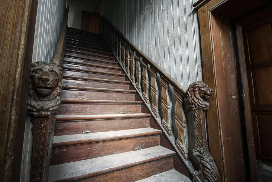 Escalera de madera con cabezas de león talladas en la barandilla
