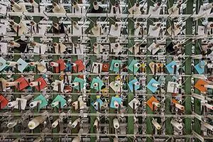 Yarn holders with coloured parts in a dense metal grid.