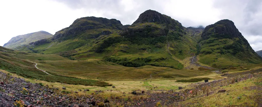 Grüner Bergkessel des Lost Valley mit dunklen Felsgipfeln und hellem Weg über dem Talboden.