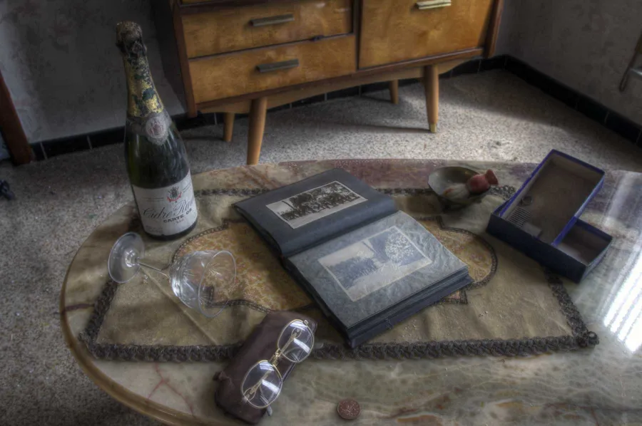 Flasche, Gläser und Fotoalbum auf einem niedrigen Tisch.