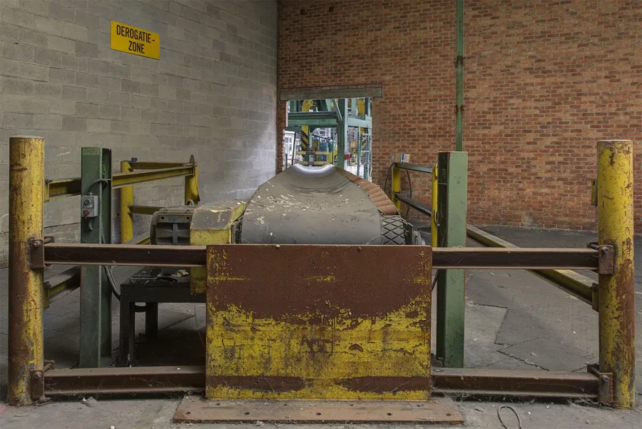 Grote metalen schijf achter gele en bruine leuningen.