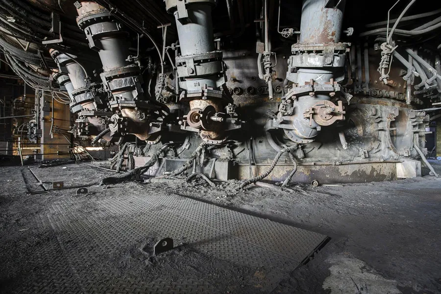 Rangée de grosses conduites inclinées au pied du haut fourneau.