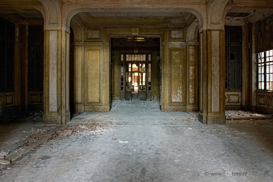 Portes successives dans un couloir vide à moulures décoratives.