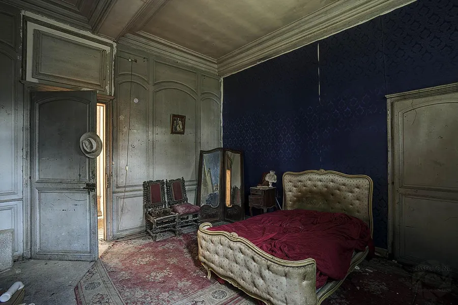 Bed with a red blanket beside mirrors and wooden doors