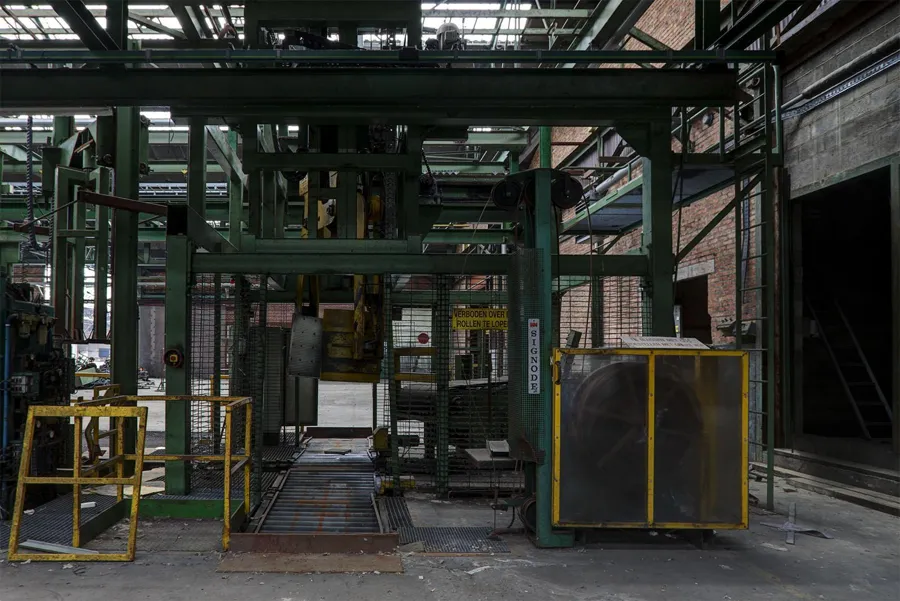 Groene stalen persconstructie met gele veiligheidshekken.