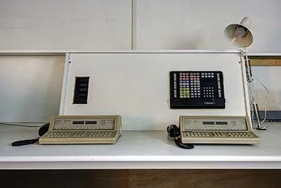 Front view of two telephone units and a panel on a sloping backboard.