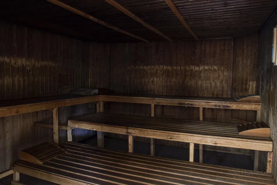 Sauna oscura de madera con bancos a distintas alturas.