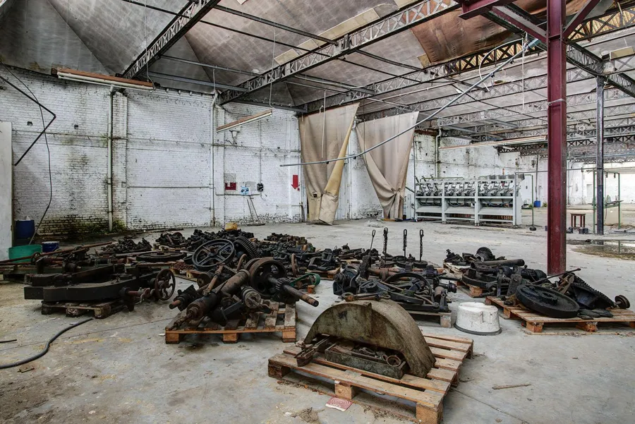 Piezas de maquinaria sueltas sobre palés de madera en una nave grande.
