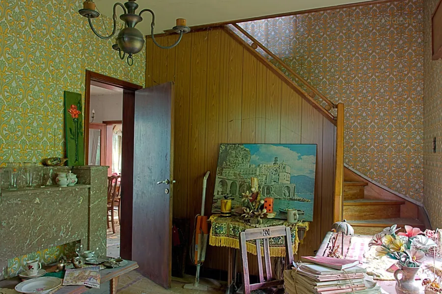 Room with a wooden stair partition, chandelier and objects on tables