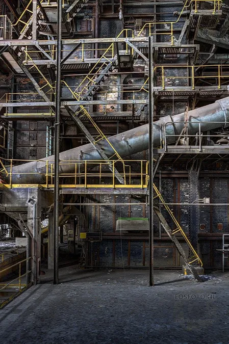 Large network of pipes and several stairs with yellow railings.