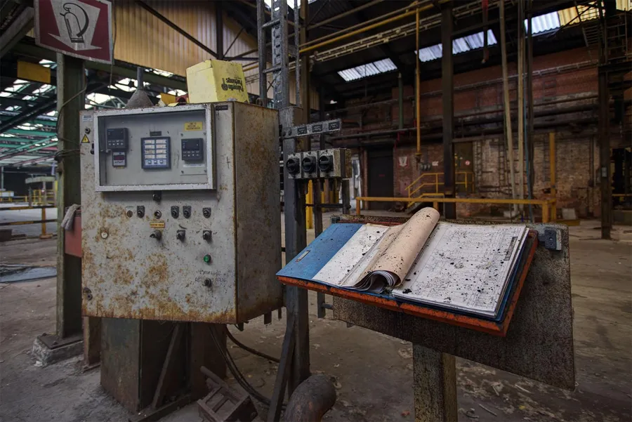Bedieningskast en opengeslagen handleiding naast een machine.