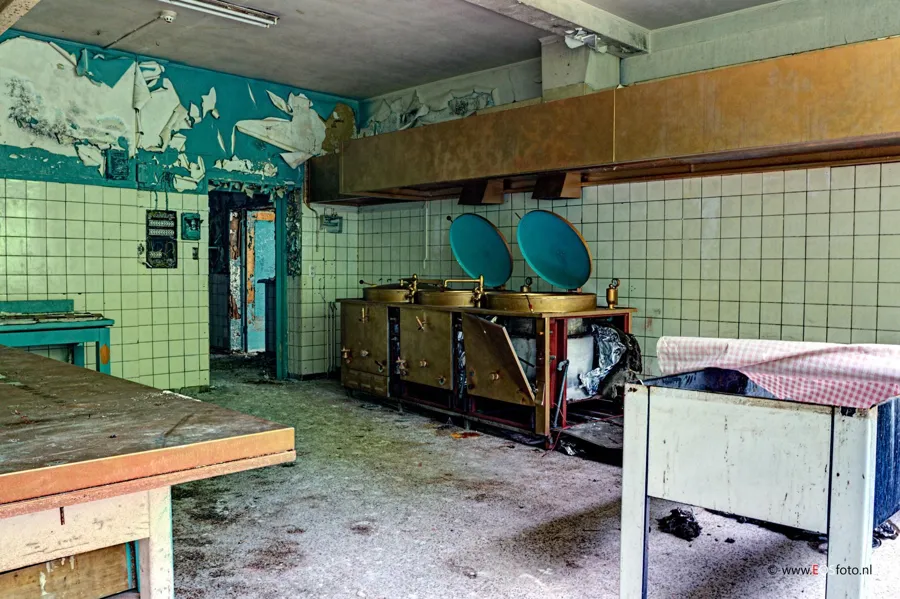 Oude keuken met grote kookketels en blauwe open deksels.