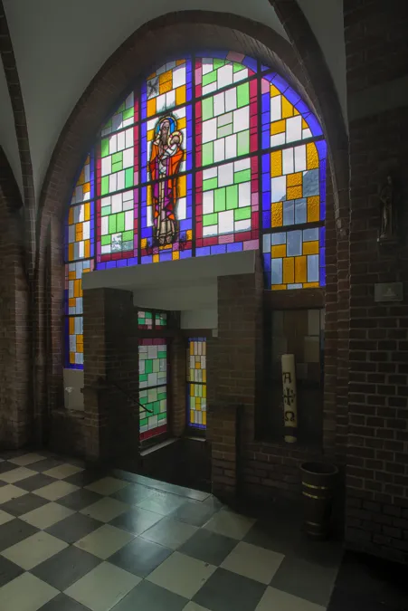 Puerta bajo una gran vidriera geométrica.