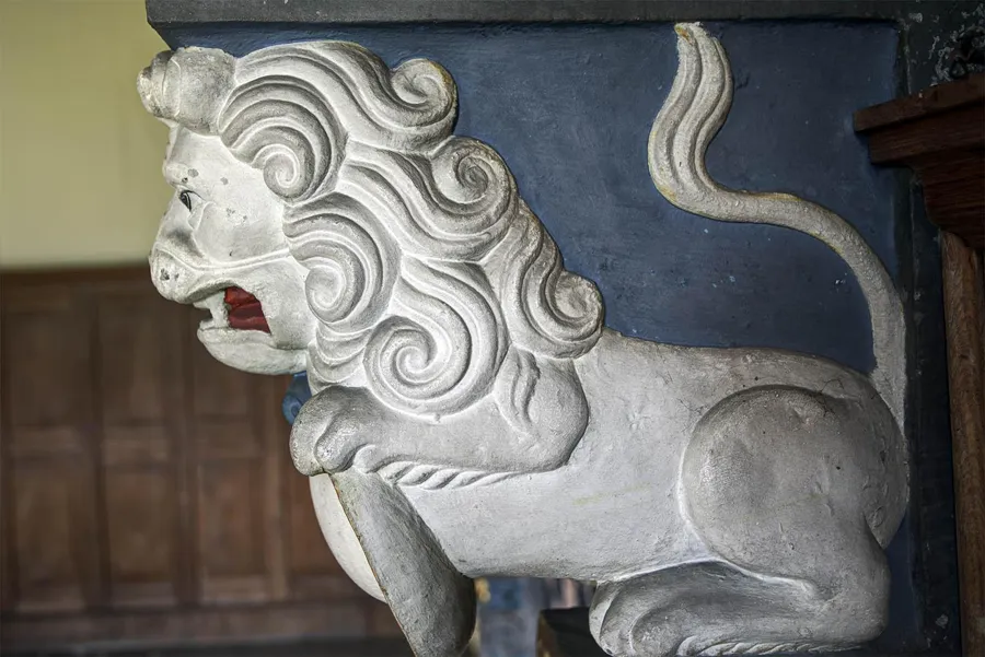 Figura de león blanco junto a una chimenea con paneles de madera