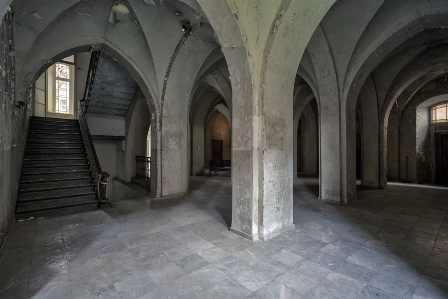 Vestíbulo con bóvedas ojivales, columna central y escalera izquierda.