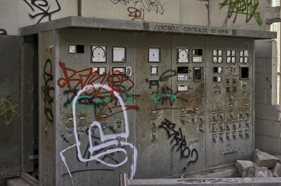 Oud bedieningspaneel met meters, schakelaars en graffiti.