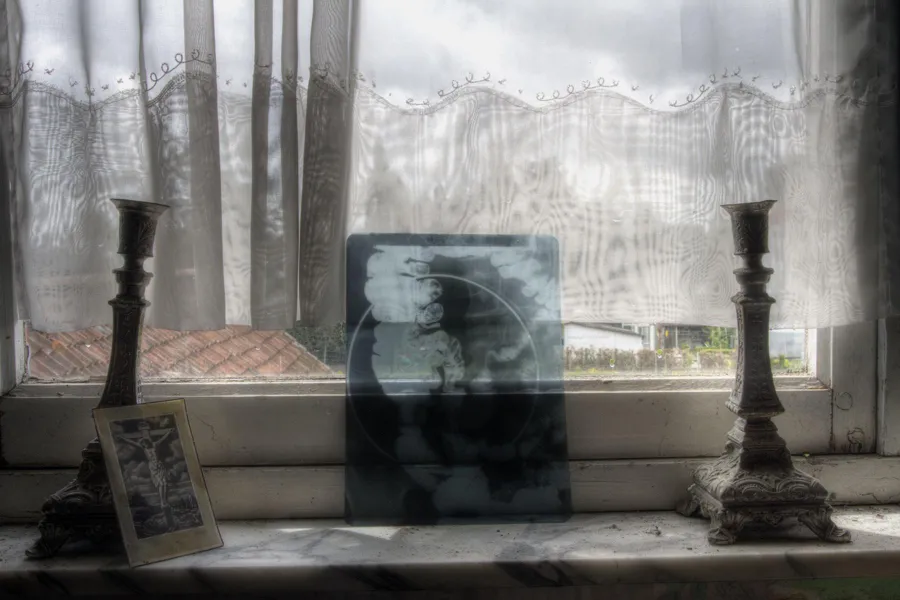 Zwei Kerzenständer und kleine Bilder auf einem Fensterbrett.