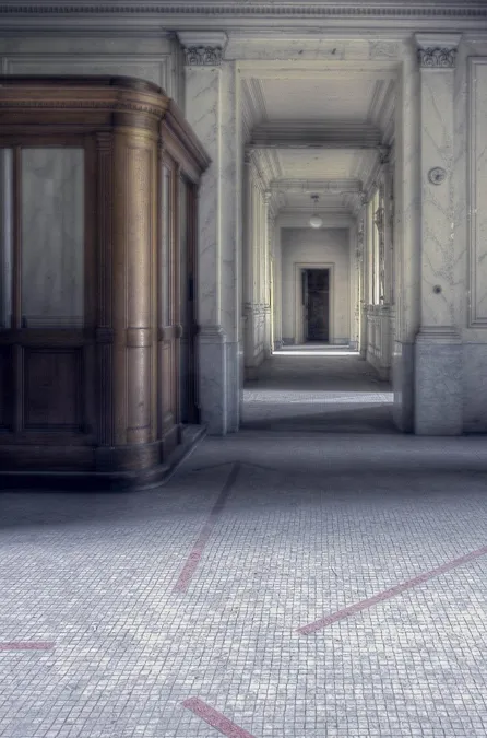 Long passage between ornate doorways and a wooden display cabinet.