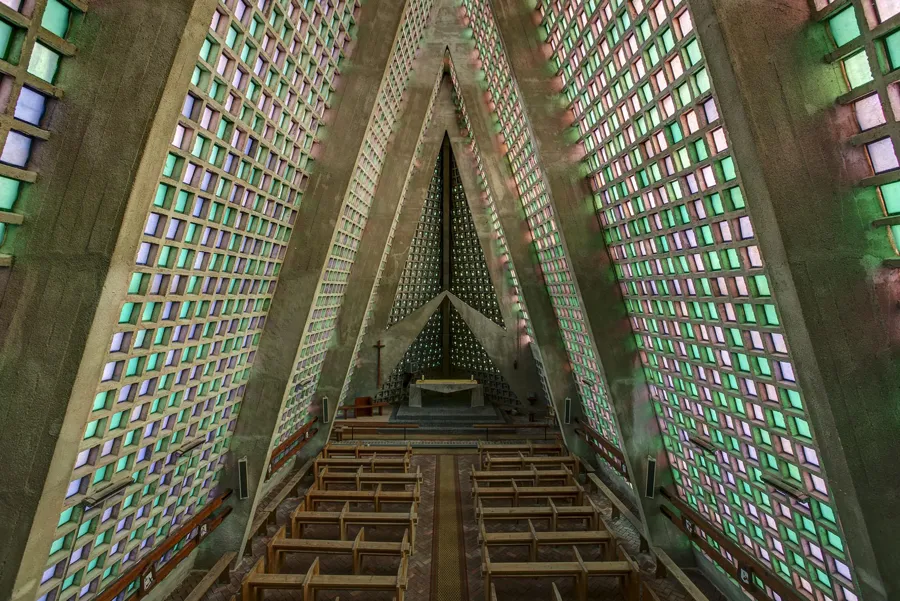 Vista amplia de iglesia triangular con paredes de vidrio verde claro.