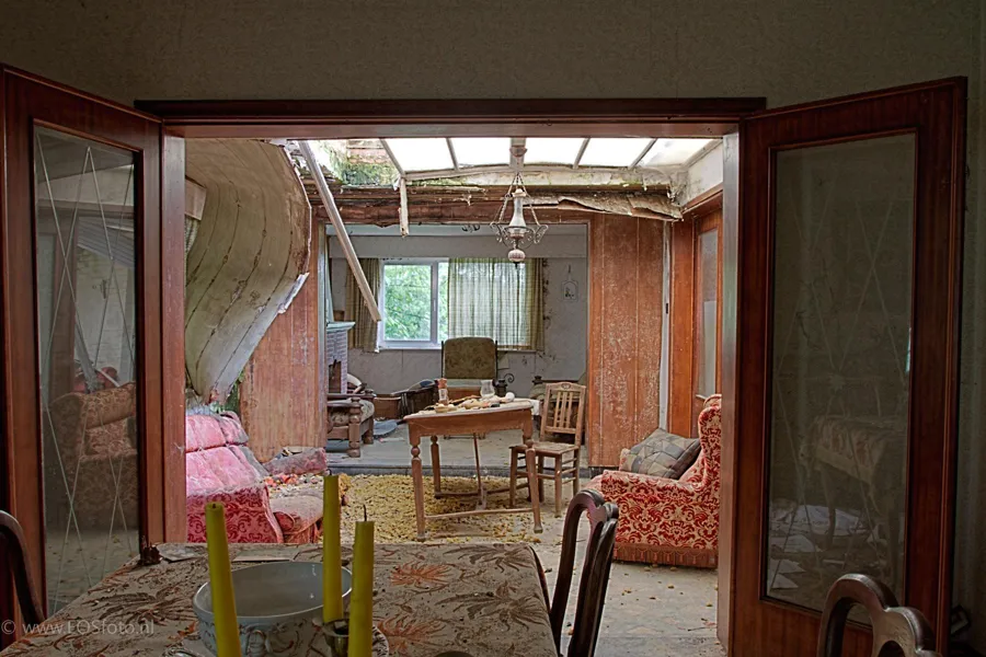 View through double doors into a sitting room beneath a damaged translucent roof
