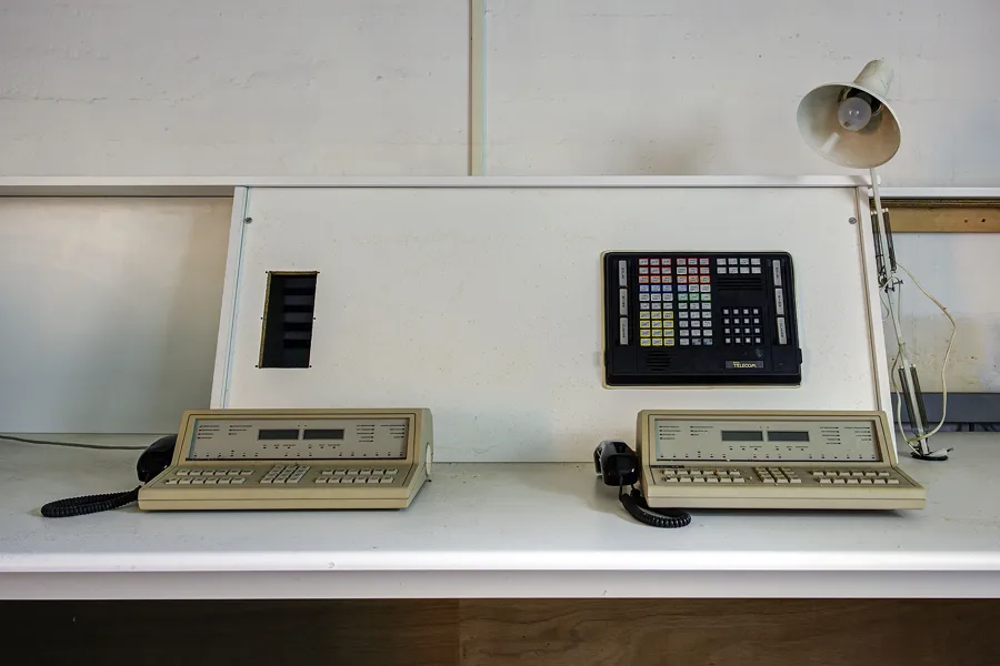 Vooraanzicht van twee telefoontoestellen en een paneel op een schuine achterwand.